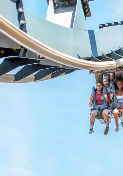 Persone su una montagna russa in corsa, sorridenti e divertite.