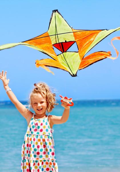 Bambina felice con aquilone colorato sulla spiaggia.