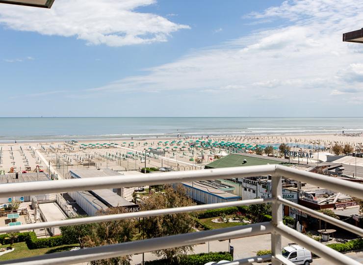 Panoramablick auf einen Strand mit grünen Sonnenschirmen.