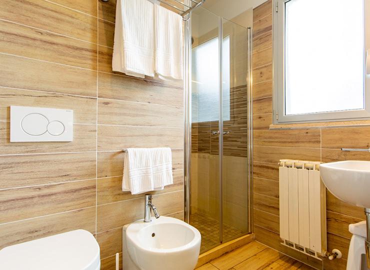 Modernes Badezimmer mit Dusche, Bidet und Waschbecken, holzverkleidet.