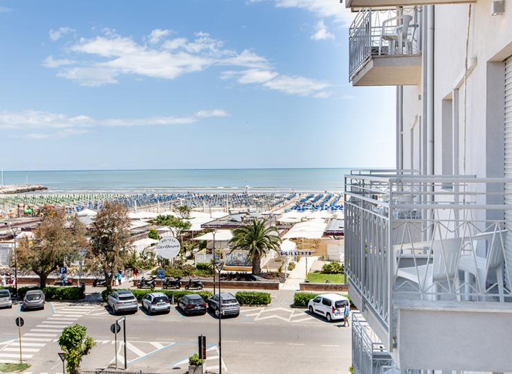 Meerblick mit Strand und Balkonen, klarer Himmel.