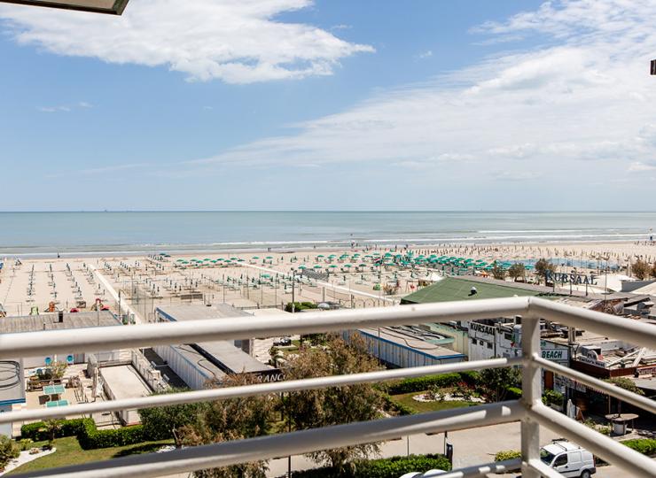 Panoramablick auf einen Strand mit grünen Sonnenschirmen.