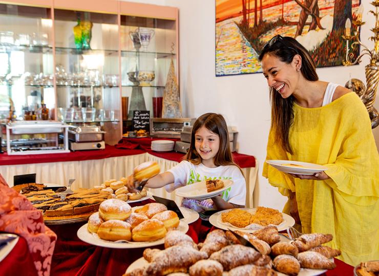 Mutter und Tochter wählen Süßigkeiten von einem reichhaltigen, bunten Buffet.