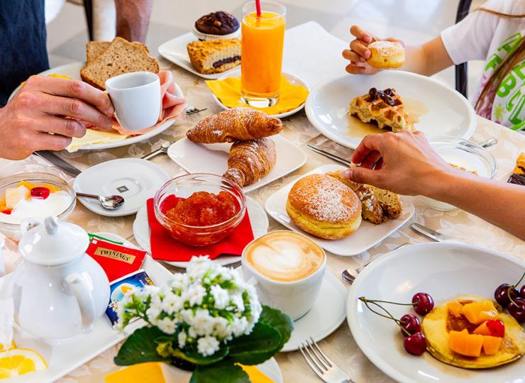 Vielseitiges Frühstück mit Gebäck, Obst und heißen Getränken.