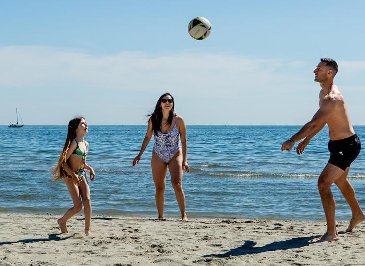 Familie spielt Volleyball am Strand.