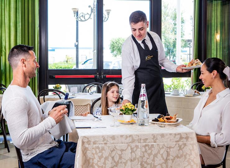 Familie beim Essen im Restaurant mit Kellner.